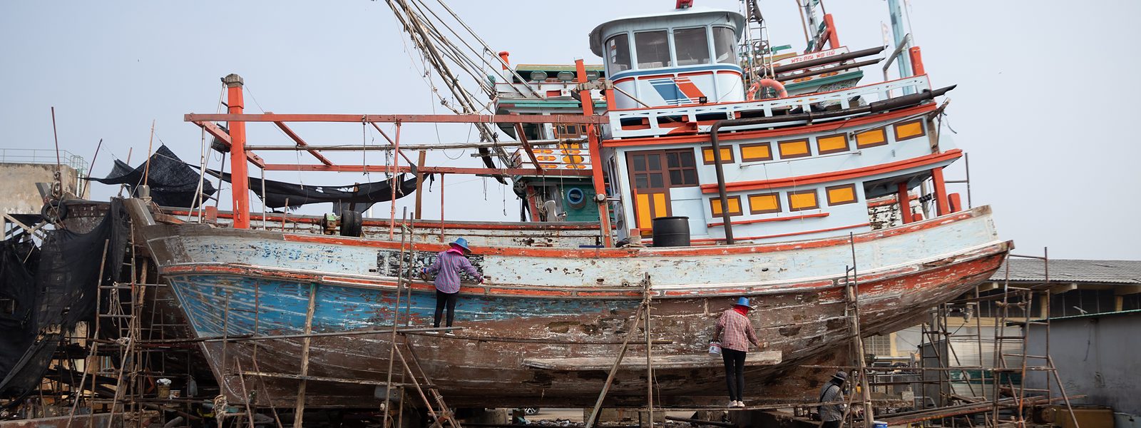 เรือประมงบนคานเรือ พนักงานขัดและทาสีตัวเรือ